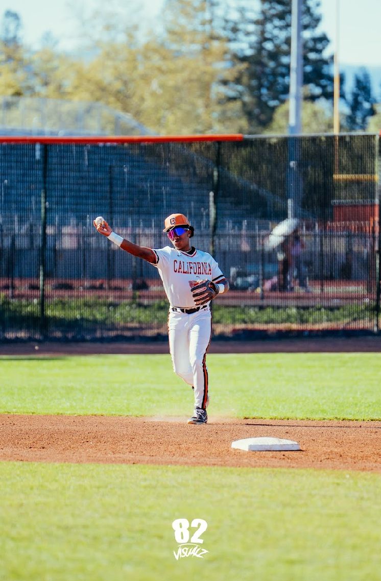 Kai Watts throwing from the middle infield in the white home uniform